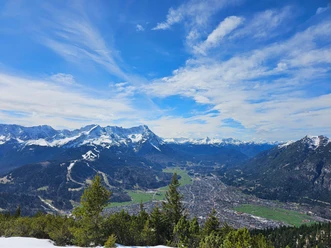 Blick auf Garmisch-Partenkirchen Blick über Garmisch-Partenkirchen vor schneebedeckten Alpen unter blauem Himmel