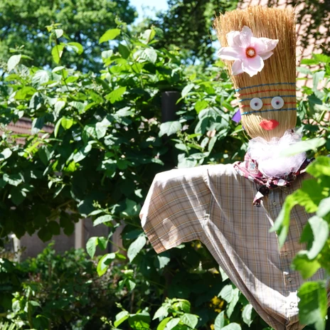Bauerngarten Rühle in Meppen ©Emsland Tourismus GmbH (6).jpg Strohfigur mit Hemd und Blüte im Bauerngarten, umgeben von dichtem Grün bei sonnigem Wetter