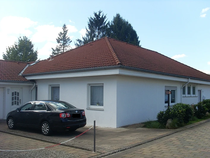 Hausansicht der Ferienwohnung Katzenberger Das Bild zeigt die Außenansicht des Hauses der Ferienwohnung Katzenberger. Das Haus ist weiß und hat ein rotes Dach. Vor dem Haus befindet sich ein Parkplatz.
