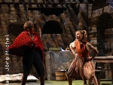 Zwei Schauspieler auf einer Bühne in einer dramatischen Szene eines rustikalen Theaterstücks.