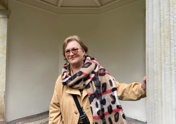 Stadtführerin Cornelia Lack Stadtführerin Cornelia Lack steht in einem überdachten Bereich und trägt einen gepunkteten Schal.