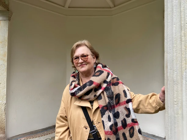 Stadtführerin Cornelia Lack Stadtführerin Cornelia Lack steht in einem überdachten Bereich und trägt einen gepunkteten Schal.