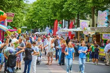 Lindenthaler-Familien-und-Veedelsfest_Krzysztof-Swider _S3-3238.jpg Lebhaftes Straßenfest in Köln, Familien genießen bunte Stände und fröhliche Atmosphäre.