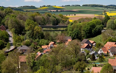 Blick ins Tal, Talbrücke Kuventhal Blick über Kuventhal mit der Talbrücke, umgeben von Feldern, Wäldern und roten Hausdächern.