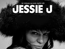 Musikerin Jessie J mit Fellhut, verschmitztem Lächeln und schwarzen, gepflegten Nägeln.