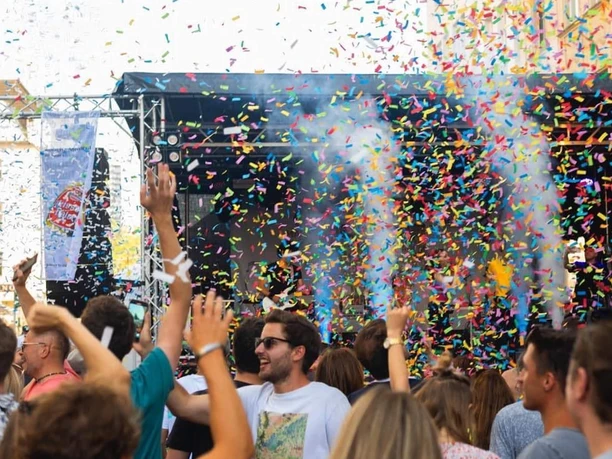 Südstadtfest Cologne People dance in front of a stage at the Südstadt Festival in Cologne, enveloped in colorful confetti.