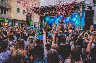 Südstadtfest Cologne A colorful crowd celebrates in front of a stage with a live band, colorful confetti floating in the air.