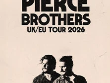 Zwei Musiker der Pierce Brothers stehen nebeneinander mit ernsten Gesichtern vor hellem Hintergrund.