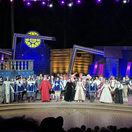 Freilichtbühne Meppen, 3 Musektiere - Das Musical 2024 ©Emsland Tourismus GmbH (3).jpeg Ensemble in historischen Kostümen auf der Bühne der Freilichtbühne Meppen unter farbigem Licht