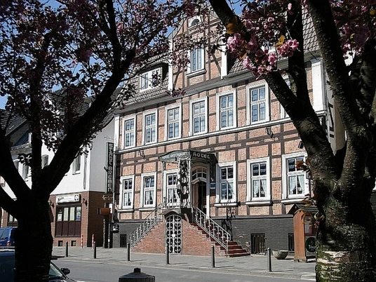 Hotel Stadt Bremen Historisches Fachwerkgebäude mit blühenden Bäumen im Vordergrund, zentrale Treppe zum Eingang.