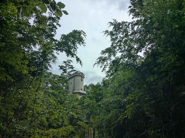 Kaiser Friedrich Turm Kaiser Friedrich Turm aus hellem Stein, umgeben von dichtem grünen Laubwald unter wolkigem Himmel.