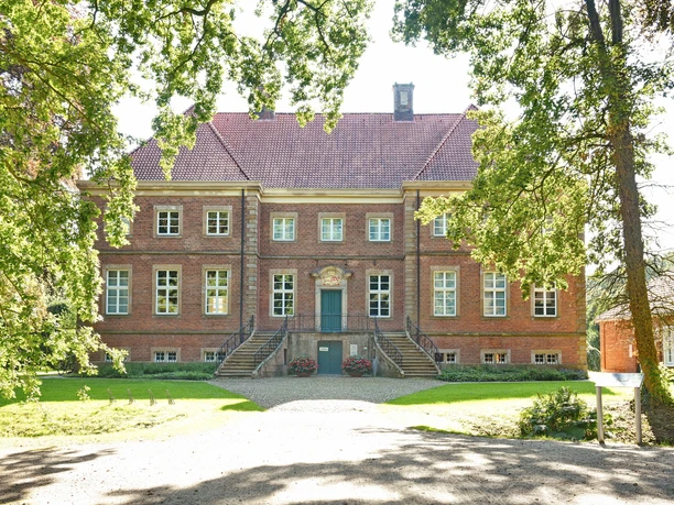Gut Altenkamp.JPG Backsteingebäude mit barocker Fassade, breiter Freitreppe und gepflegtem Garten im Vordergrund