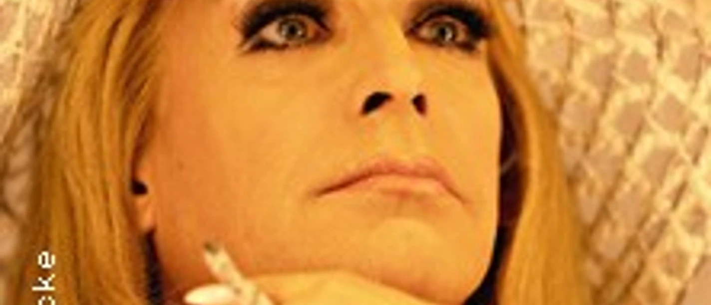 Porträt einer Person mit Hut, fokussiert denkend, hält eine Zigarette, hintergründiger, softer Kontrast.