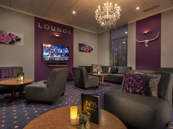 Lounge im Restaurant Brasserie, Mettmann Restaurantlounge mit eleganter Beleuchtung, lila Akzenten und gemütlichen Sitzgruppen für Gäste.