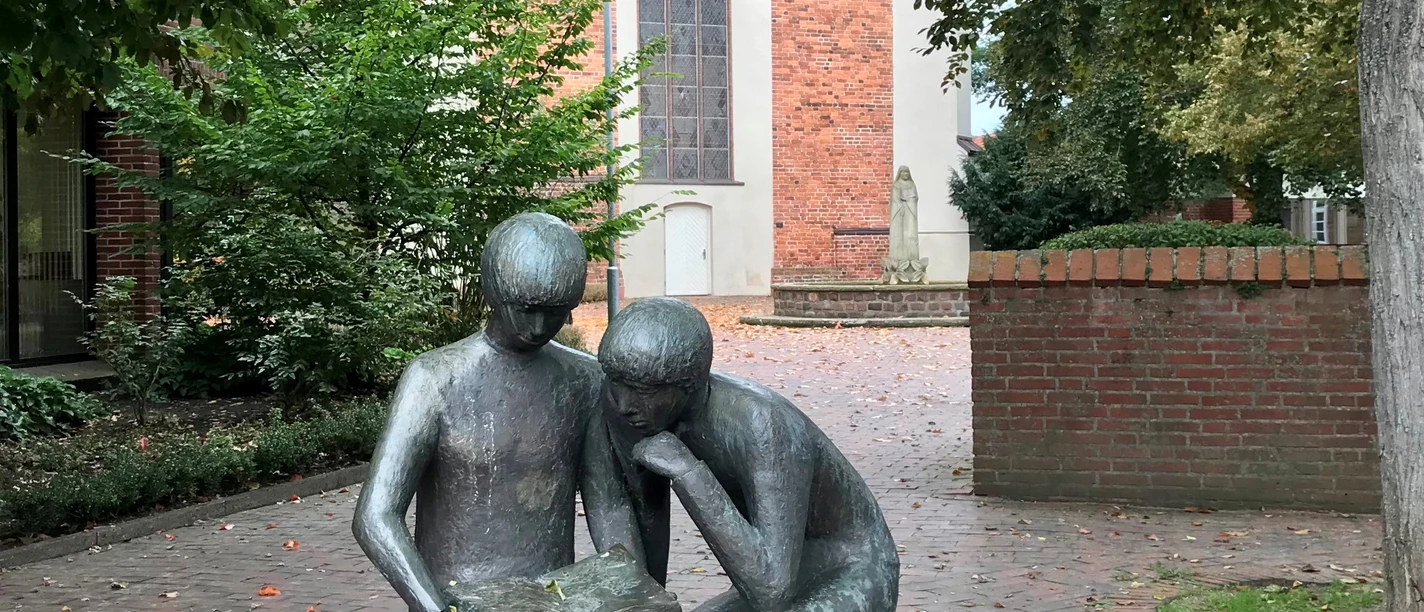 Skulptur Jan und Lili vor der Klosterkirche Sculpture of a man and a woman sitting on a bench in front of the monastery church