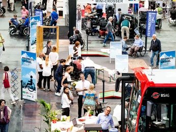 BSAG-und-Perspektivwechsel-©-Escales-Verlag.jpg Ein gut besuchter Messestand mit Rollstühlen, Fahrzeugen und barrierefreien Informationen.A well-attended stand with wheelchairs, vehicles and barrier-free information.Hojně navštěvovaný výstavní stánek s vozíky, vozidly a informacemi o bezbariérovosti.Licznie odwiedzane stoisko wystawowe z wózkami inwalidzkimi, pojazdami i informacjami bez barier.Een drukbezochte beursstand met rolstoelen, voertuigen en informatie over barrières.Uno stand espositivo ben frequentato con sedie a rotelle, veicoli e informazioni sull'assenza di barriere.