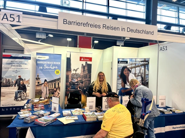 IRMA Bremen_3.jpg Ein Messestand für barrierefreies Reisen in Deutschland mit Rollstuhlfahrern und Infomaterial.