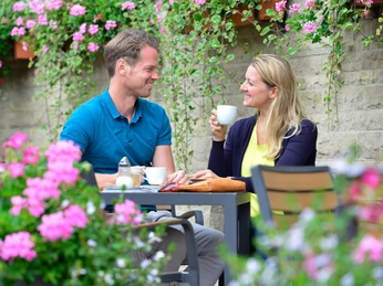 Paar Kaffeetrinken Gifhorn.jpg Mann und Frau mit zwei Kaffeetassen in der Hand beim Kaffetrinken in einem Lokal in Gifhorn.