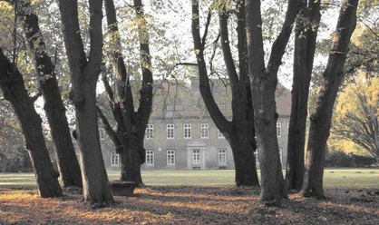 Historisches Gutshaus in Cadenberge, umgeben von altem Baumbestand im herbstlichen Gutspark.