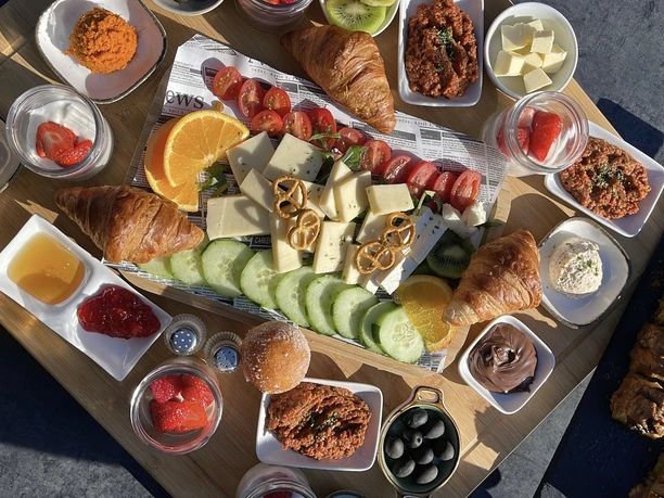 Gastro_Titelbild_Café-Blackbird_Kaan Karakus.jpeg Vielfältiges Frühstücksangebot mit frischem Obst, Backwaren, Aufstrichen und Oliven.