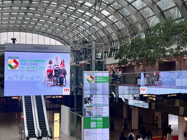 REHACARE Düsseldorf2024_Eingangshalle Messe Nord.jpg Eingangshalle der Messe Düsseldorf zur REHACARE 2024 mit Besuchern und farbigem Boden.