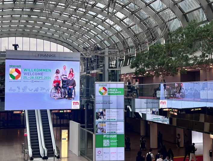 REHACARE Düsseldorf2024_Eingangshalle Messe Nord.jpg Eingangshalle der Messe Düsseldorf zur REHACARE 2024 mit Besuchern und farbigem Boden.Entrance hall of Messe Düsseldorf for REHACARE 2024 with visitors and colored floor.Vstupní hala veletrhu REHACARE 2024 v Düsseldorfu s návštěvníky a barevnou podlahou.Hol wejściowy Messe Düsseldorf na targi REHACARE 2024 z odwiedzającymi i kolorową podłogą.Entreehal van Messe Düsseldorf voor REHACARE 2024 met bezoekers en gekleurde vloer.Ingresso della Messe Düsseldorf per REHACARE 2024 con visitatori e pavimento colorato.