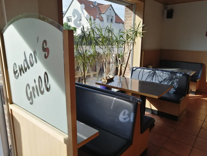 Enders Fleischerimbiss_Pro Herford (3).jpg Ein heller Imbiss mit Holzinterieur und Pflanzen, einladender Sitzbereich und Glaswände für viel Licht.