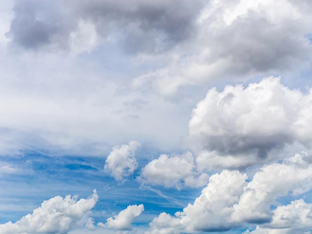 Wolken.jpg Weiße Wolken ziehen über einen klaren, blauen Himmel, vereinzelt von grauen Wolken durchsetzt.