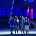 Freilichtbühne Meppen, 3 Musektiere - Das Musical 2024 ©Emsland Tourismus GmbH (2).jpeg Vier Musketiere in blauen Kostümen stoßen mit Schwertern auf der Freilichtbühne unter blauem Licht an.