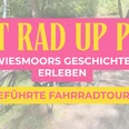 Destination.one (1920 x 1080 px) (2).png Zusehen ist schwach im Hintergrund ein Fahrrad und Bäume und ein Sand-weg, im Vordergrund steht in Orangener Schrift auf einem kräftigen Rosa Schild "Mit Rad up Pad" und darunter in weißer Schrift Wiesmoors Geschichte Erleben und darunter in Pinker Schrift auf orangenen Schild geschrieben "geführte Fahrradtour".