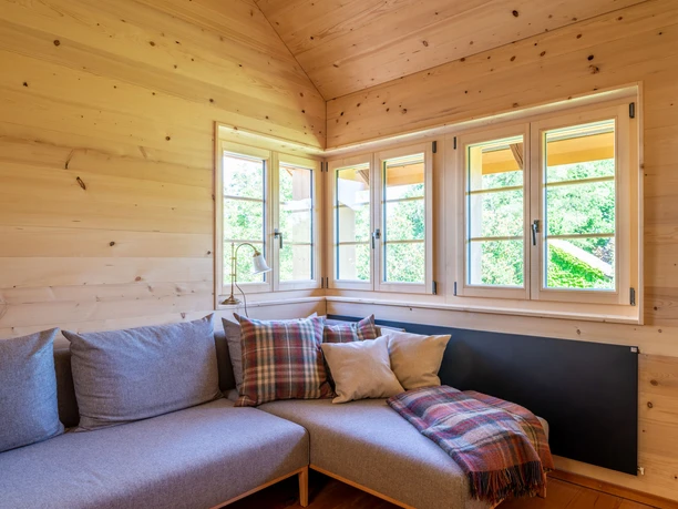 Neue Holzfenster in Wohnzimmer Drei Holzfenster in Wohnzimmerecke über grauem Ecksofa