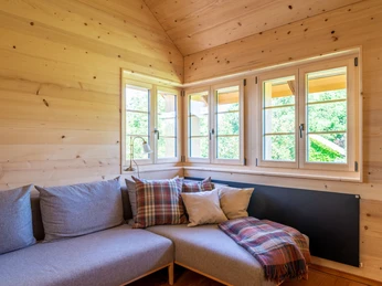 New wooden windows in living room Drei Holzfenster in Wohnzimmerecke über grauem EcksofaThree wooden windows in living room corner above grey corner sofaTrois fenêtres en bois dans un coin du salon au-dessus d'un canapé d'angle gris