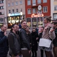 Eine fröhliche Gruppe erkundet lächelnd die Altstadt von Köln, umgeben von historischen Gebäuden und typisch kölschen Brauhäusern.A cheerful group smiles as they explore Cologne's old town, surrounded by historic buildings and typical Cologne breweries.