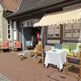 Café La Vie En Rose Café mit farbenfrohen Kissen und gestreifter Markise an einer historischen Fachwerkfassade.