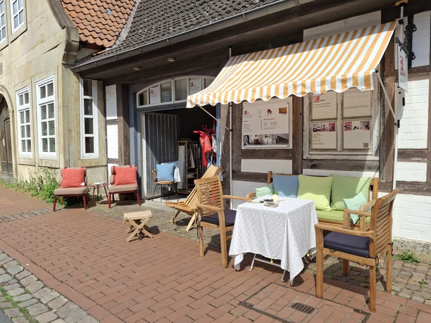 Café La Vie En Rose Café mit farbenfrohen Kissen und gestreifter Markise an einer historischen Fachwerkfassade.