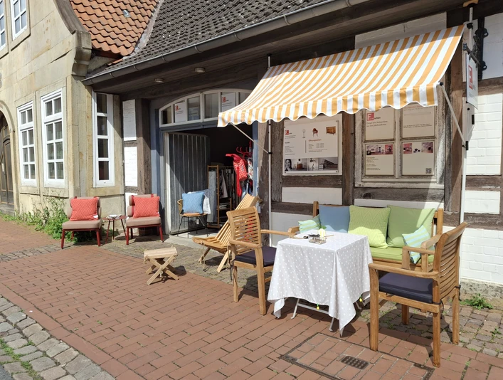 Café La Vie En Rose Café mit farbenfrohen Kissen und gestreifter Markise an einer historischen Fachwerkfassade.