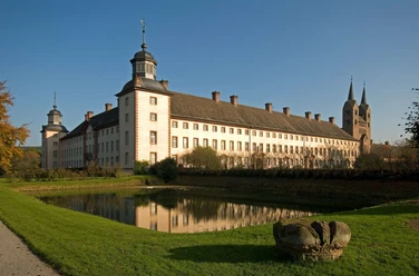Schloss Corvey mit seinen imposanten Türmen spiegelt sich im ruhigen Wassergraben wider.