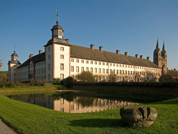 Schloss Corvey mit seinen imposanten Türmen spiegelt sich im ruhigen Wassergraben wider.