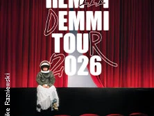 Auf einem roten Theatervorhang prangt der Schriftzug "Remmi Demmi Tour 2026". Eine Person sitzt vor der Bühne.