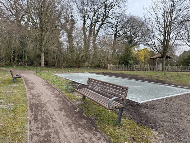 Bouleplatz im Frühjahr, Backemoor, Gemeinde Rhauderfehn IMG_7931.JPG Leerer Bouleplatz im Frühjahr in Backemoor mit zwei Holzbänken entlang eines Weges und kahlen Bäumen im Hintergrund