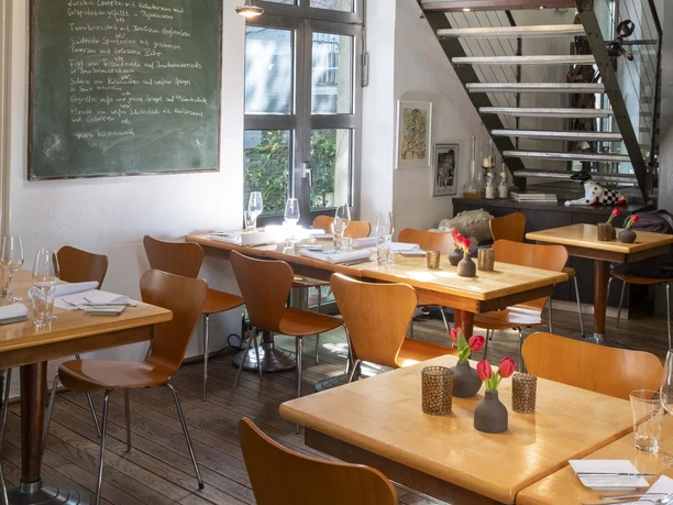 Christoph Pauls Restaurant Innenansicht eines stilvollen Restaurants mit Holztischen, modernen Stühlen und einer kunstvollen Dekoration.