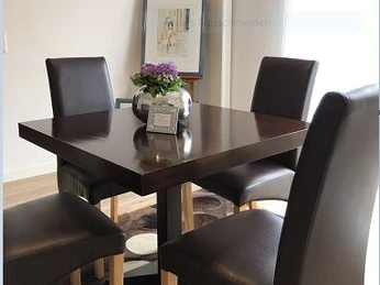 Ferienwohnung Caprice Moderner dunkelbrauner Tisch mit vier dunkelbraunen, elegant gepolsterten Stühlen in stilvollem Essbereich.