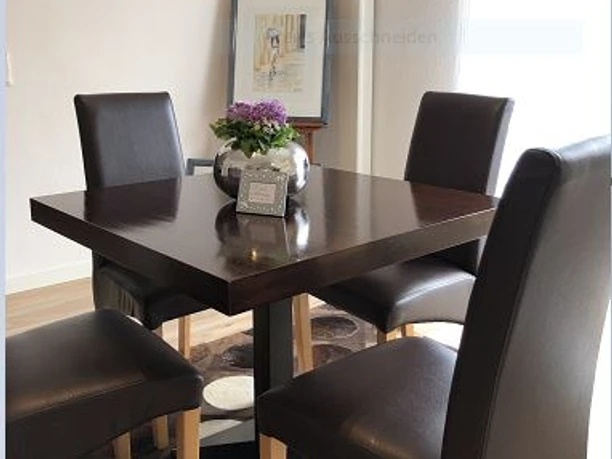Ferienwohnung Caprice Moderner dunkelbrauner Tisch mit vier dunkelbraunen, elegant gepolsterten Stühlen in stilvollem Essbereich.