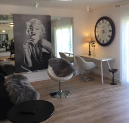 Ferienwohnung Caprice Stilvolle, moderne Drehsessel aus Leder neben einem Schreibtisch, unter einem Marilyn Monroe Bild.