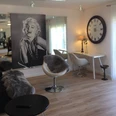 Ferienwohnung Caprice Stilvolle, moderne Drehsessel aus Leder neben einem Schreibtisch, unter einem Marilyn Monroe Bild.
