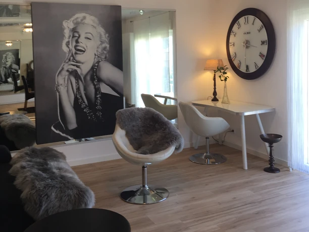 Ferienwohnung Caprice Stilvolle, moderne Drehsessel aus Leder neben einem Schreibtisch, unter einem Marilyn Monroe Bild.