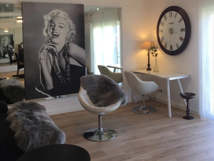 Ferienwohnung Caprice Stilvolle, moderne Drehsessel aus Leder neben einem Schreibtisch, unter einem Marilyn Monroe Bild.