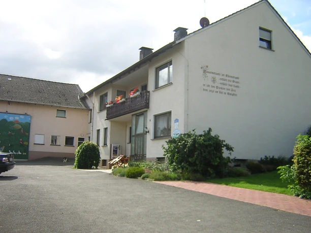 Hausansicht Bauernhof-Ferienwohnung Wüllner Hausansicht mit Balkon von der Straßenseite aus, rechts befindet sich eine gepflegte Rasenfläche