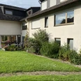 Hausansicht vom Garten - Bauernhof-Ferienwohnung Wüllner Hausansicht vom Garten aus mit grünem Pflanzenbeet und gepflegter Rasenfläche davor