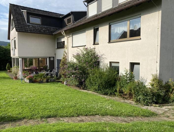 Hausansicht vom Garten - Bauernhof-Ferienwohnung Wüllner Hausansicht vom Garten aus mit grünem Pflanzenbeet und gepflegter Rasenfläche davor